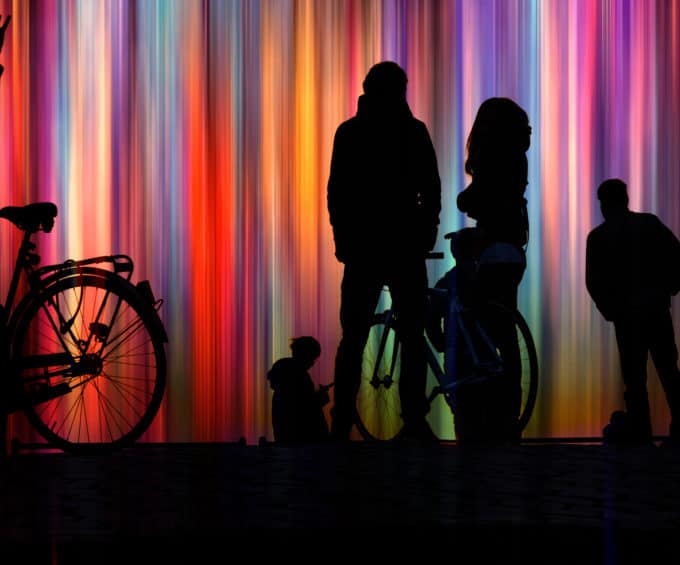 SILHOUETTE PEOPLE STANDING BY MULTI COLORED LIGHT